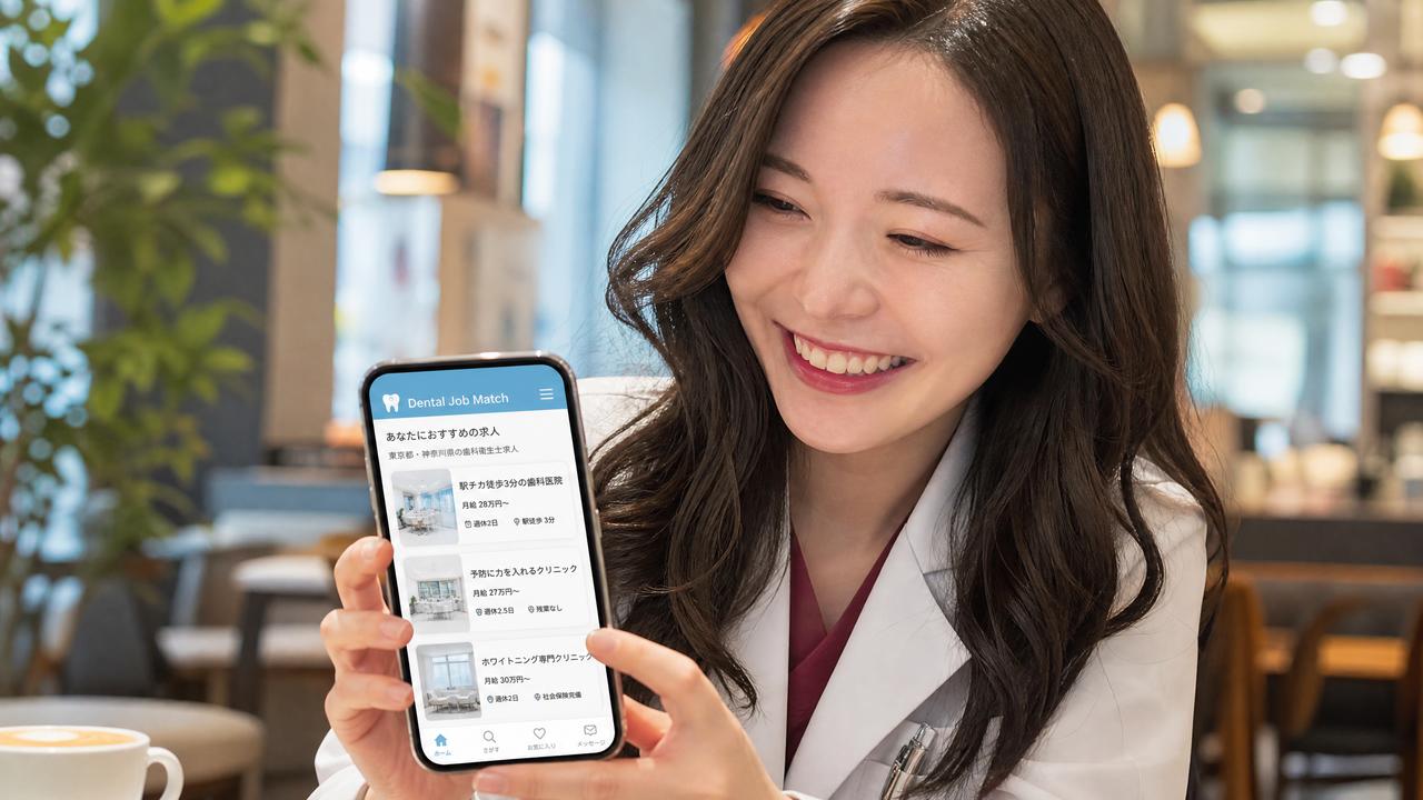 カフェでHagurumaの画面を表示したスマホを手にする歯科衛生士